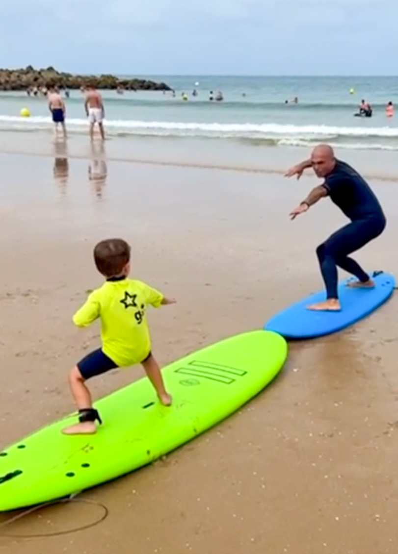 Instructor enseñando a un niño a surfear en la playa de Cádiz.